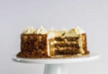 Pecan-Filled Carrot Cake Carrot Cake with a slice on a plate in front of it