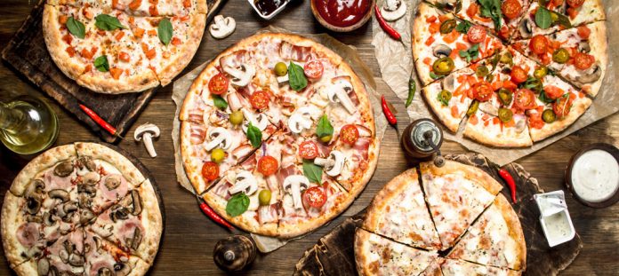 A variety of pizzas on a table as seen from above.