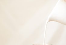 Iced Coffee with Milk A glas of Iced Coffee with Milk being poured into it from a white pitcher.