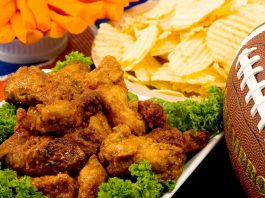 Ensure food safety while tailgating this football season Parmesan Wings with Super Bowl party snacks and a football in the background.