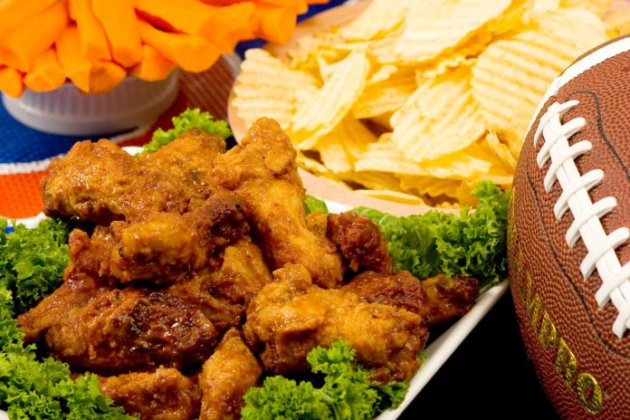 Parmesan Wings with Super Bowl party snacks and a football in the background.