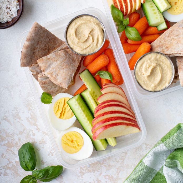 Hummus packed with fruits and vegetables for a school lunch.