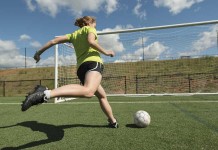 Team anger management girl kicking soccer ball into goal