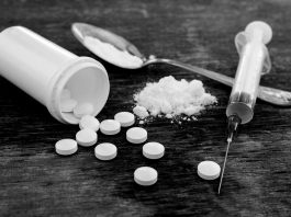 Pills, Fentynal Powder, and Heroin syringe sit on a table