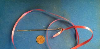 Antique pin about 6 inches long with a large rounded opening at the one end.