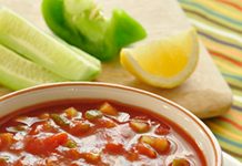 Great Gazpacho Soup A bowl of Gazpacho Soup with lemon, green pepper and cucumber in the background