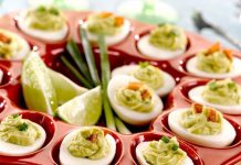 Guacamole Deviled Eggs A tray of Guacamole Deviled Eggs with cut limes in the middle of the tray.