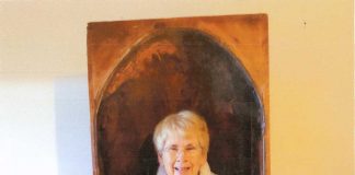 A woman stands inside of a large opening in this antique item.