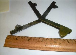 A antique metal tool about 6 inches wide that opens revealing three flat arms with triangle points on the end. 