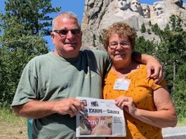 Tom White and Elizabeth Burrier stand in front of Mt. Rushmore with their Farm and Dairy newspaper in hand.