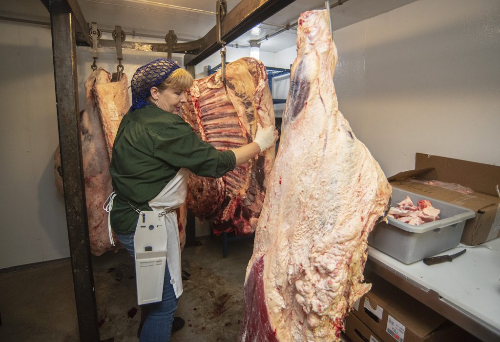 Mary Anne Kettering pulls out half a cow from the cooler.