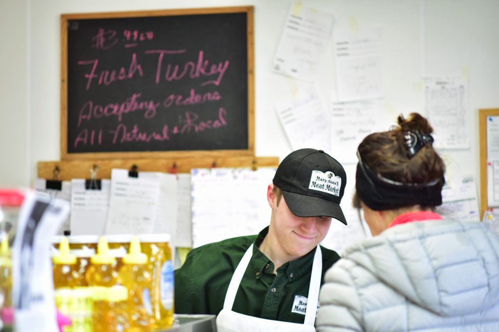 An employee at MaryAnne's Meats checks out a customer