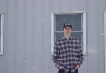 Sold on it: Baer family’s fourth generation to continue auctioneering legacy Michael Baer, 18, stands in front of a barn at Rogers Community Auction while it snows.