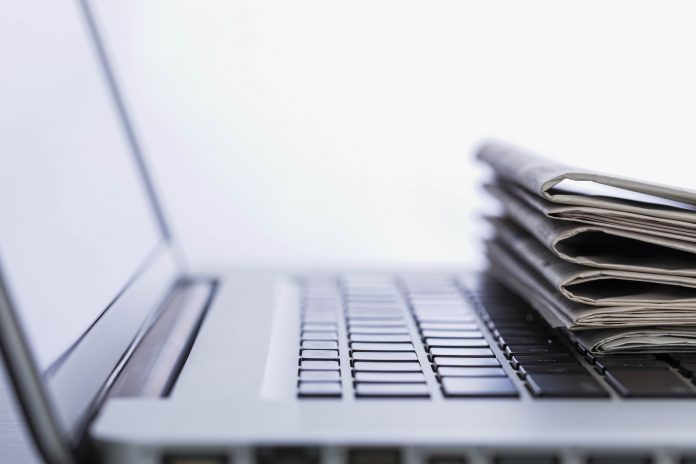 A computer with papers stacked on the keyboard.