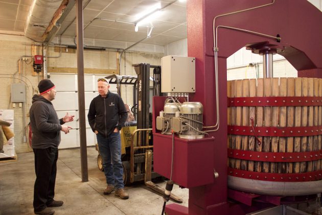 Winemaker Michael Harris and vineyard manager Gene Sigel stand in a garage near basket presses that are pressing grapes for ice wine.