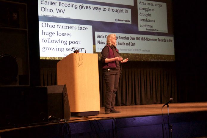 A woman stands on a stage and speaks.