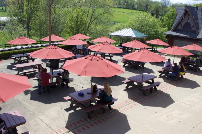 People sit at picnic tables under umbrellas.