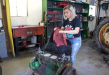 Dad’s hands and feet: Family rallies around father with disease A woman pulls a cover off of a tractor engine.