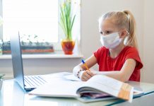 Pandemic exposes rural broadband access challenges A girl sits at a computer with a textbook.