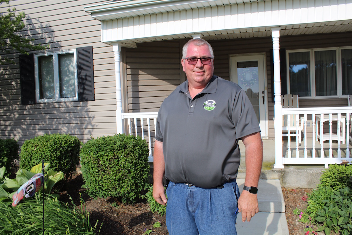 man stands in front of house