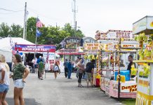 Ohio’s early fairs planning for summer, but prepared to adapt people walk up and down the midway at a fair.