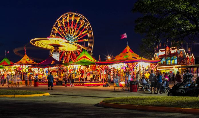 amusement rides and games with lights at a fair at night.