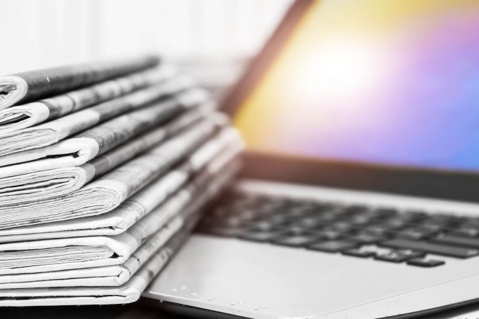 A pile of newspapers on a laptop.