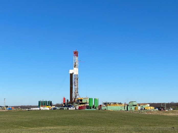 an unconventional oil and gas drilling rig sits in a green field in eastern Ohio