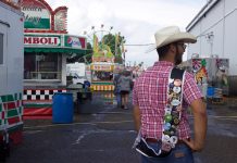 Ohio 4-H’er Brad Sheppard on journey to visit all of the state’s fairs A 4-H'er shows off pins on his fair king sash on the midway at a fair.