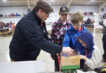 Columbiana County families learn about farm safety A woman demonstrates the hazards of grain to three children with a mini gravity wagon.
