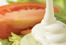 Ranch dresing pouring over a salad.