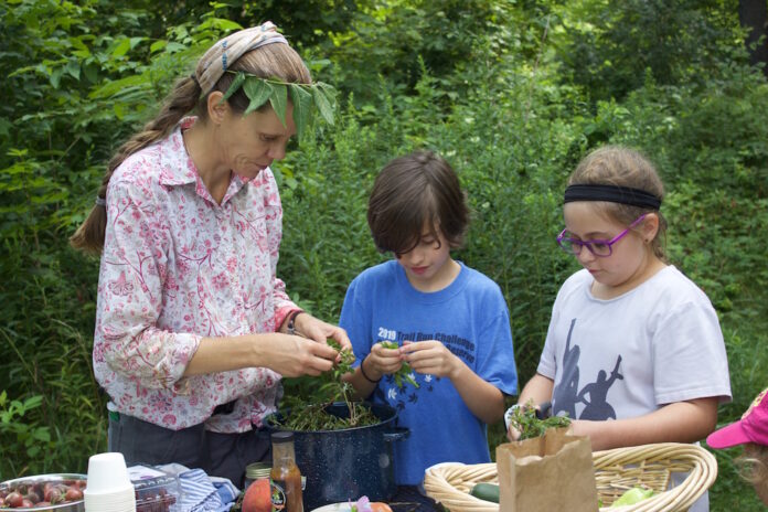 a woman and two children cutting up ingredients for a salad.