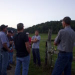 Grace Meadows Farm uses pasture management to grow contract grazing, beef cattle operations A group of farmers stand near a fence at a beef cattle farm.