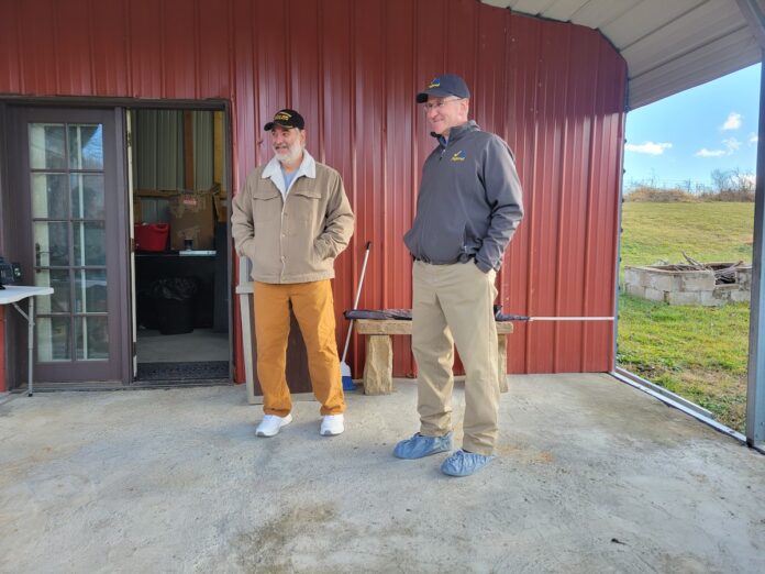 two men standing together in front of a farm store