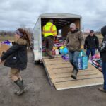 Donations arrive from Indianapolis for farmers, pet owners affected by train derailment people carry donated items out of a trailer