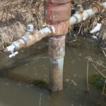 Workshops focus on finding oil and gas wells in western Pa. water sits in a trench around a well head casing. the water has bubbles on the surface.