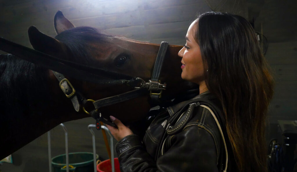 Adrianna Runzo holds her horse head as he muzzles her.