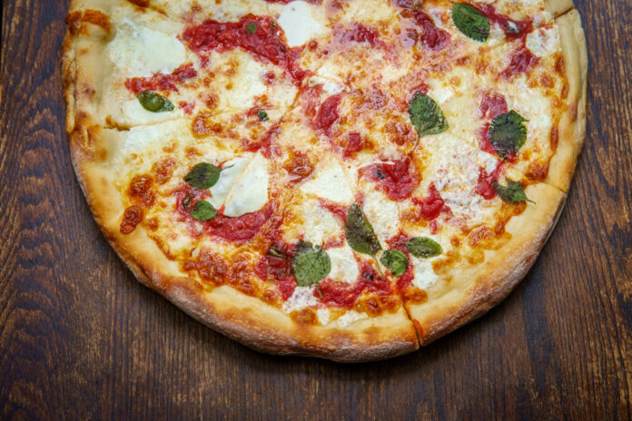 New York style Margherita pizza with fresh mozzarella and basil leaves