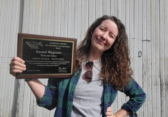 a woman stands holding an awards plaque