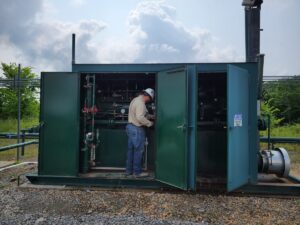 a man uses a handheld gas detector to find methane leaks in a GTU separator at an unconventional well lpad