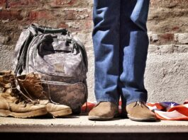 Proud veteran minimalist photography of person standing near backpack and boots
