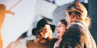 a group of three women stand together as friends