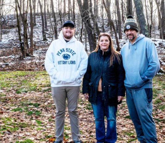 Tannar, Kimberly and Tom Barton stand in their backyard in Alicia, Pennsylvania on Dec. 7, 2025. The former Robena Coal Mine site is further up the hill.