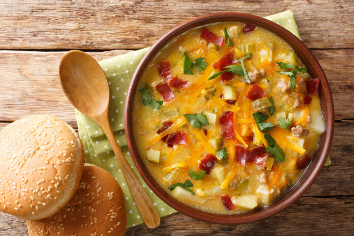 Homemade cheeseburger soup close-up in a bowl with buns. Horizon